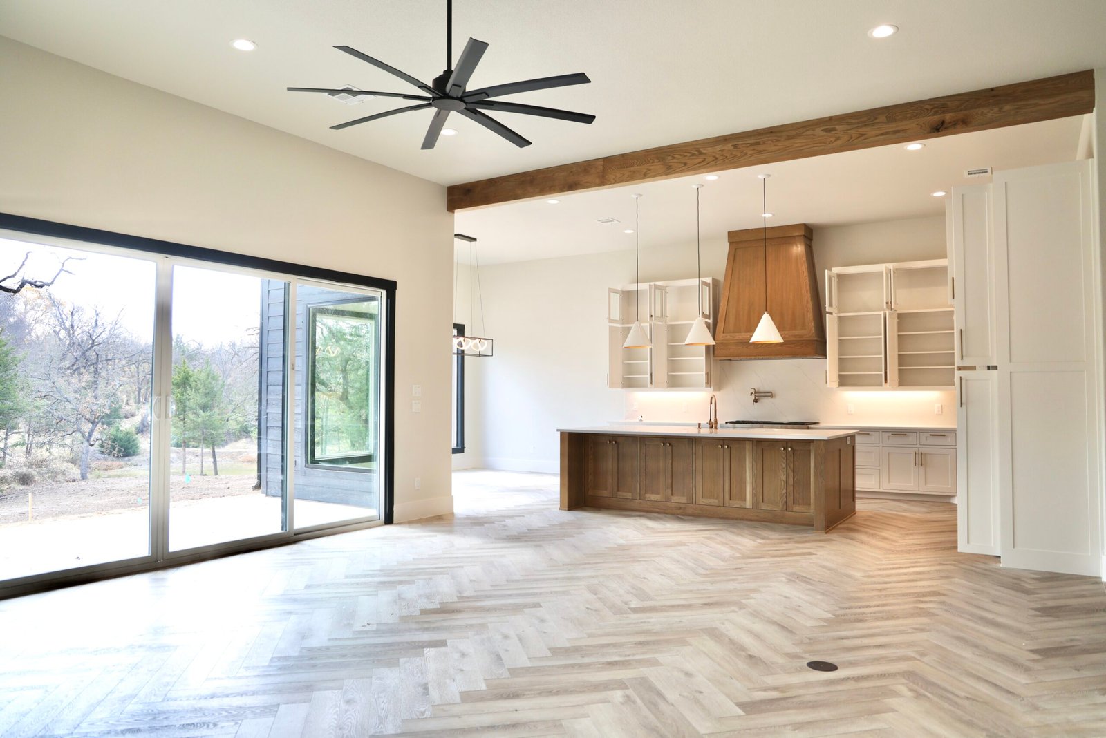 Open living room with ceiling fan and herringbone floors
